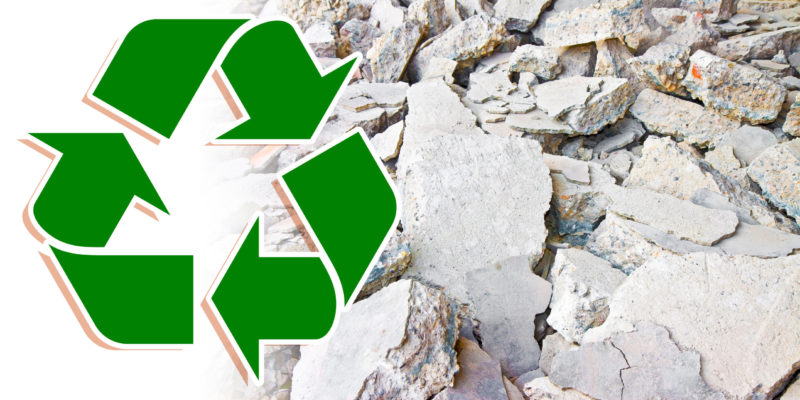 Broken concrete debris from a house demolition, with a recycling symbol.