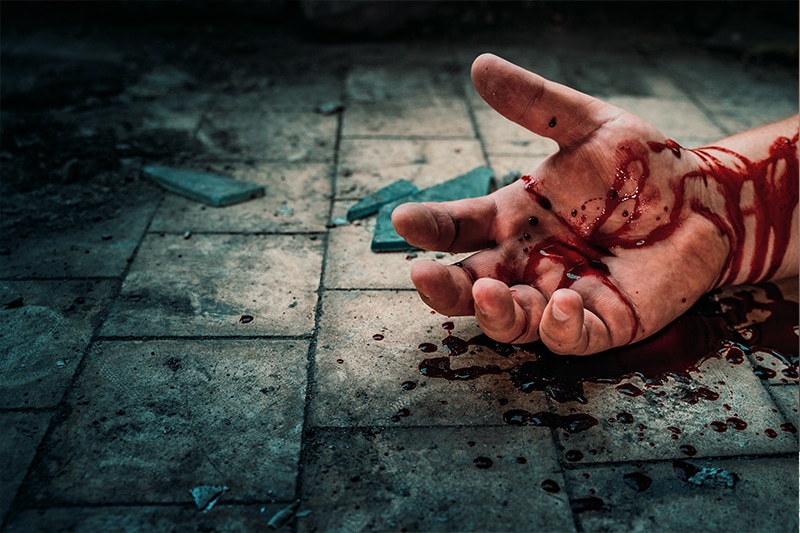 A hand with blood on it on the floor requiring trauma clean-up services.